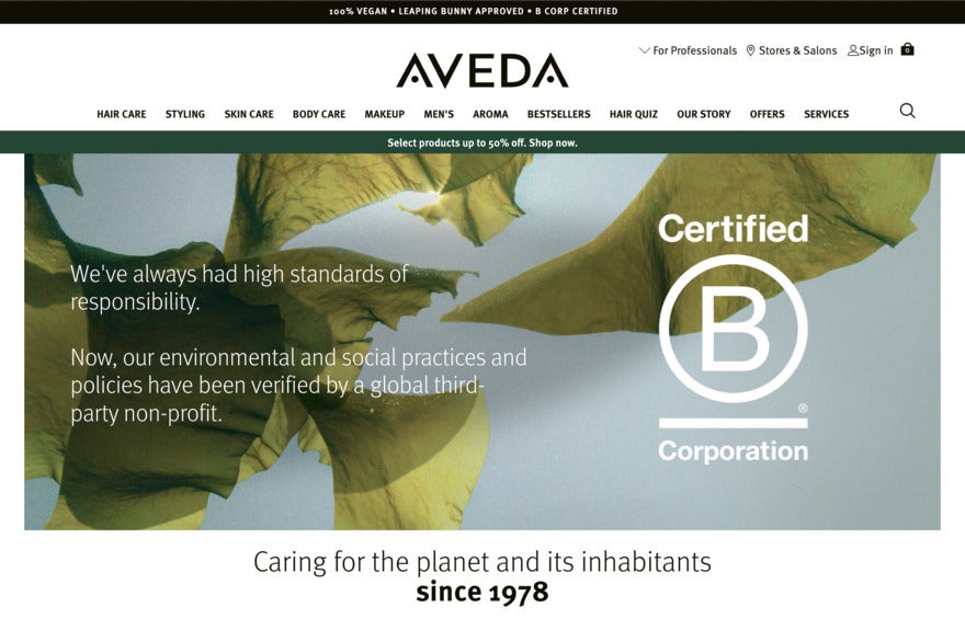 A photo of the Aveda website detailing B Corp status on top of a photograph of green leaves.