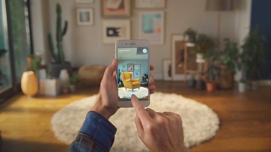 A person uses IKEA's AR tool to visualize a yellow chair in their room